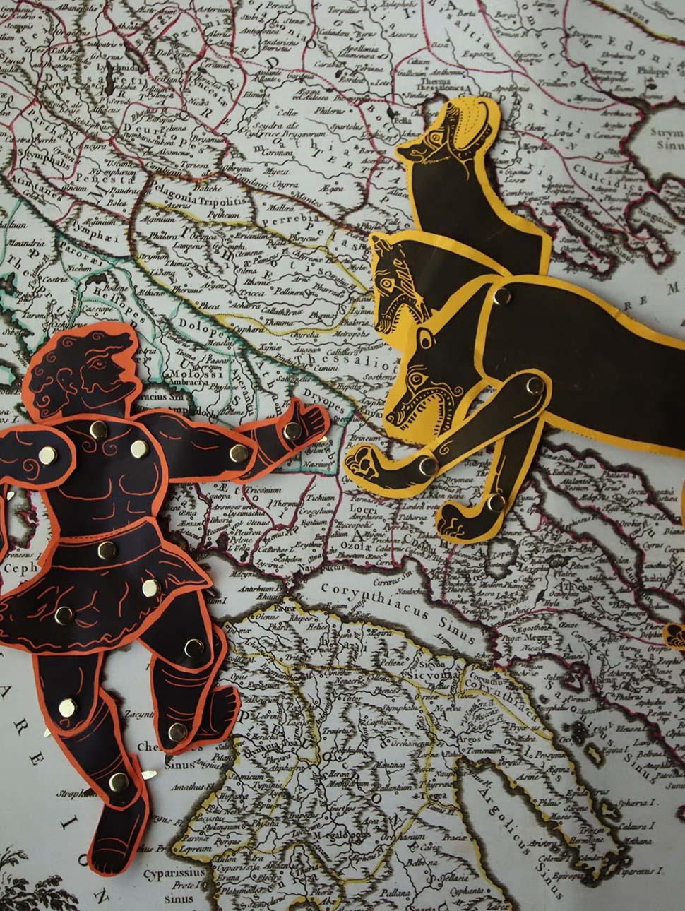 Paper cutout of monster and Greek hero on Ancient Greek map 