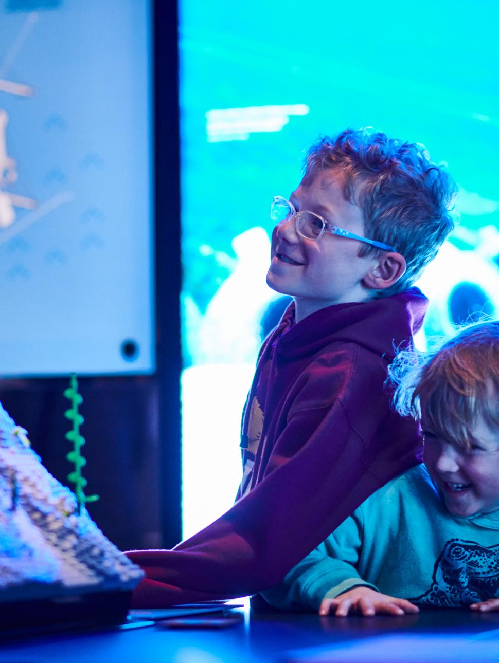 An image of two kids closely looking at a LEGO model display from Brickwrecks
