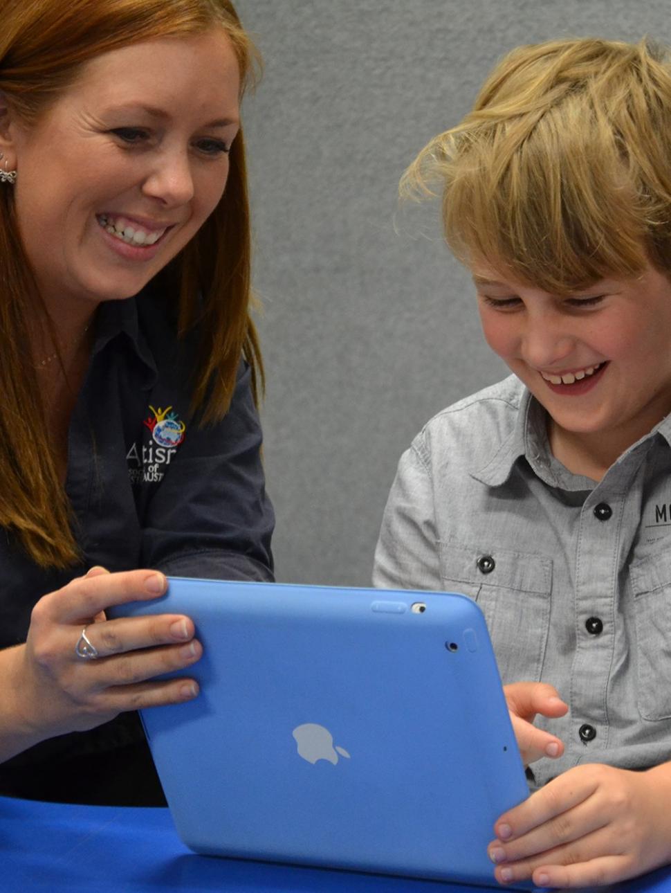 Autism WA staff member engaging with a child with an iPad