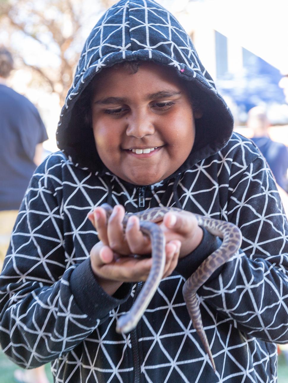 An image of a young child holding a snake