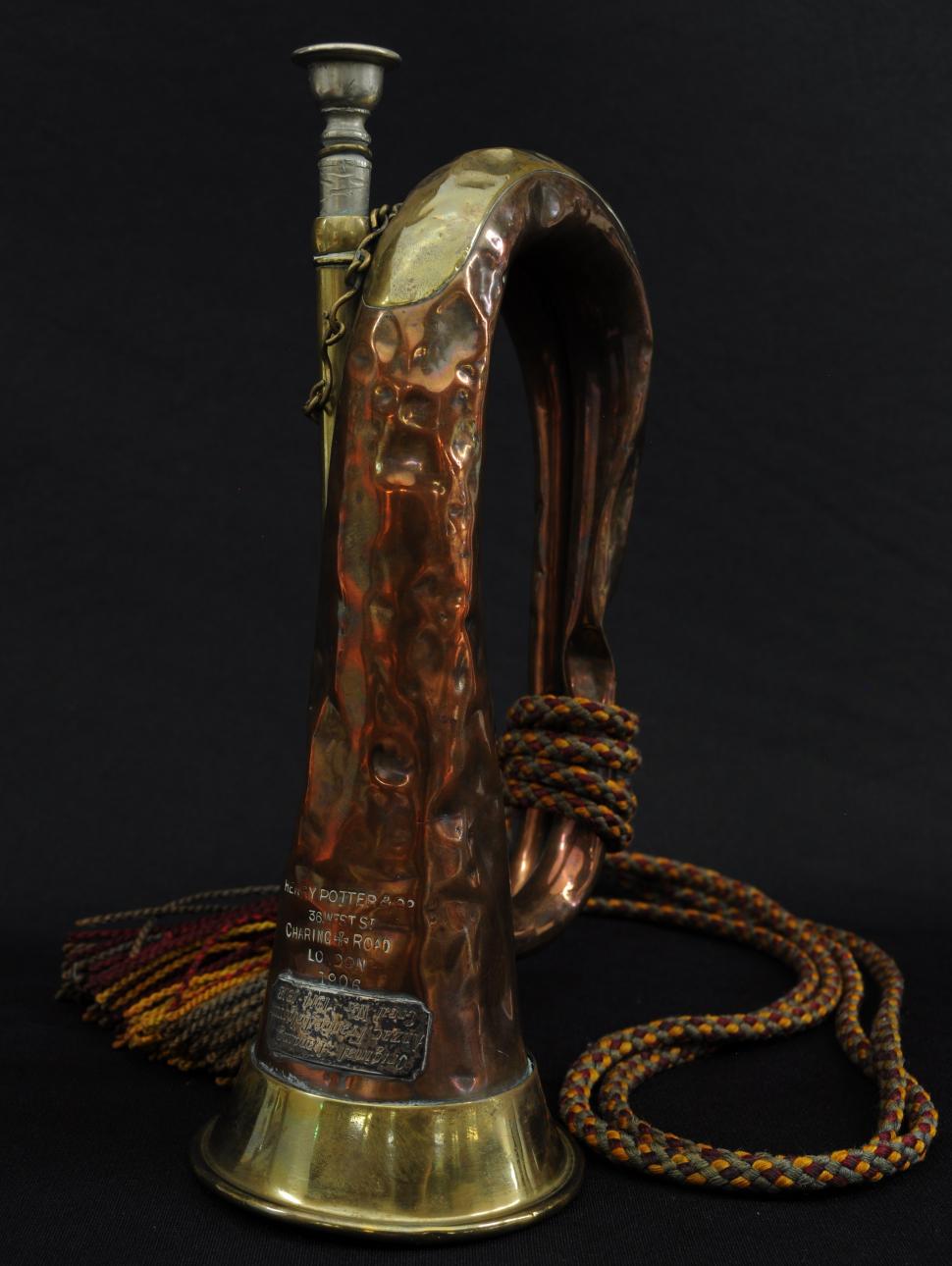 A copper bugle sits on a black surface, propped upward.