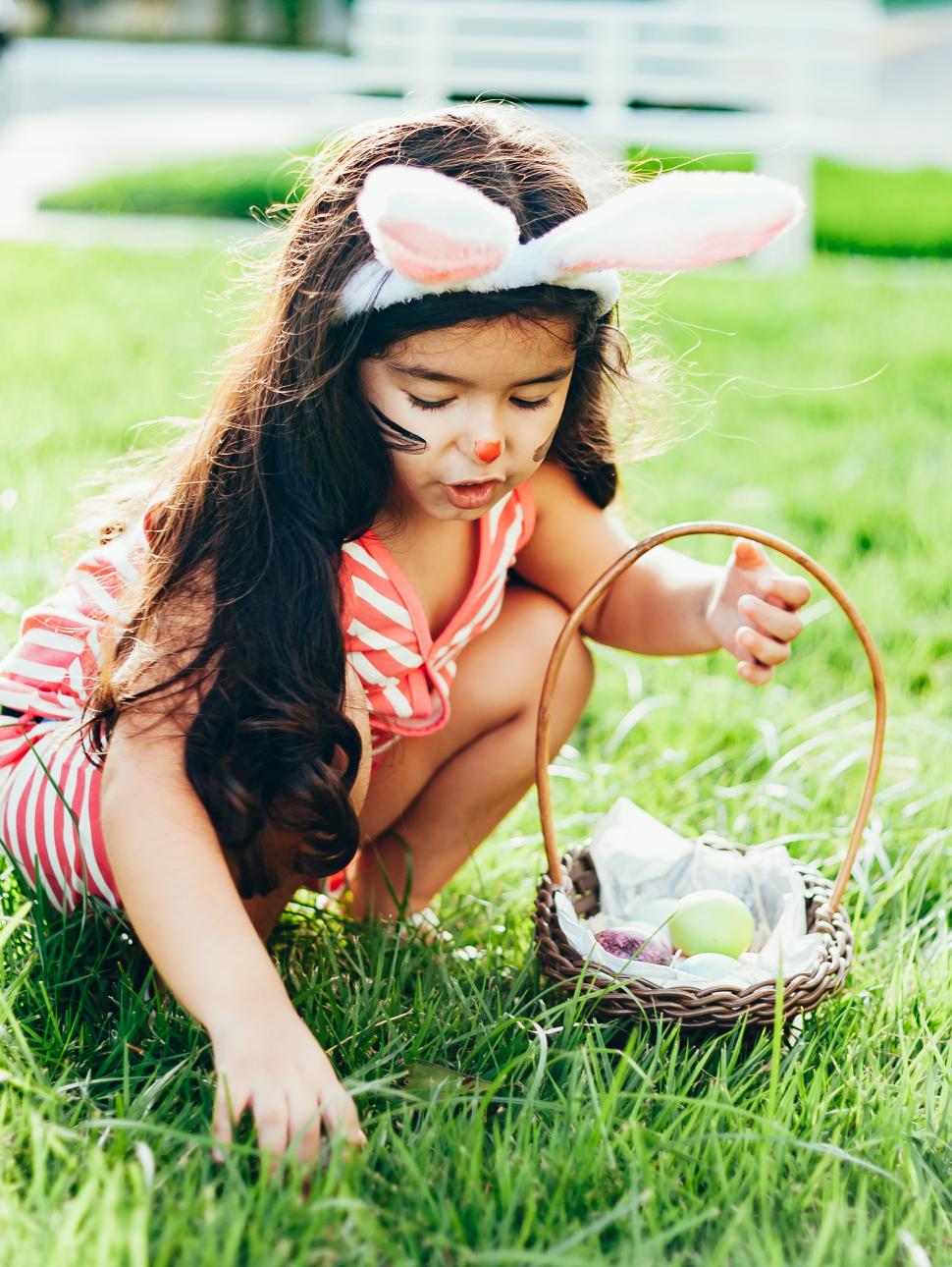 Young child dressed as a bunny looks for Easter eggs