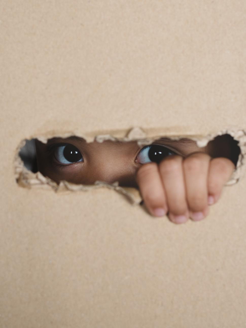 Young girl peeping through cardboard