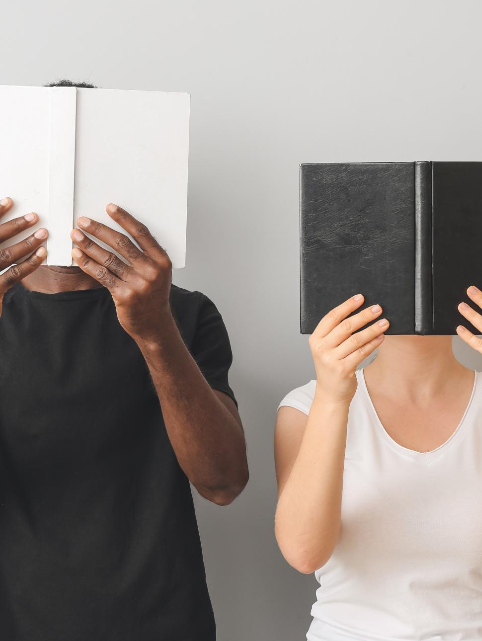 a man and a woman hold books to their face, black and white