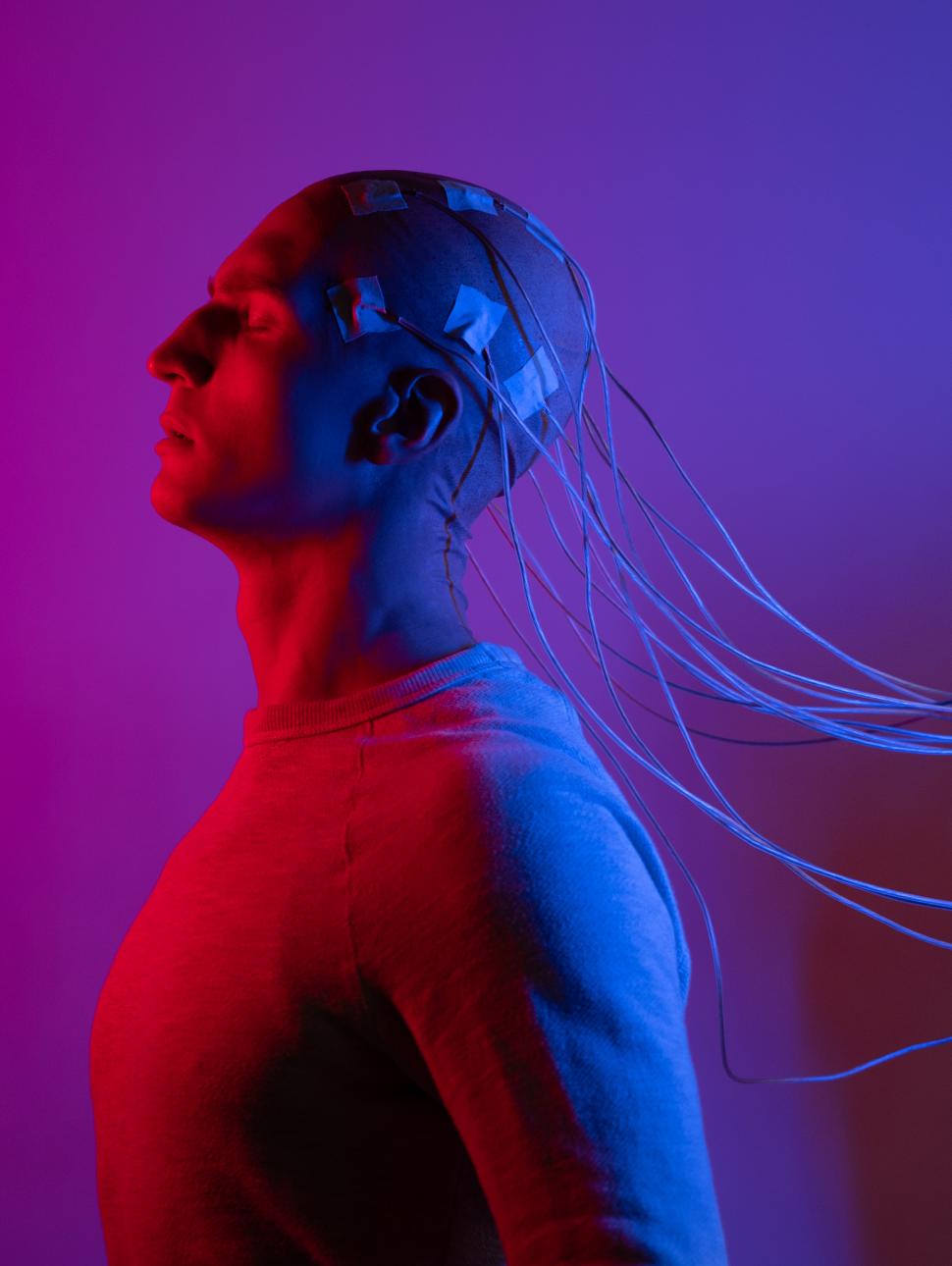 red and blue lighting of man plugged into wires