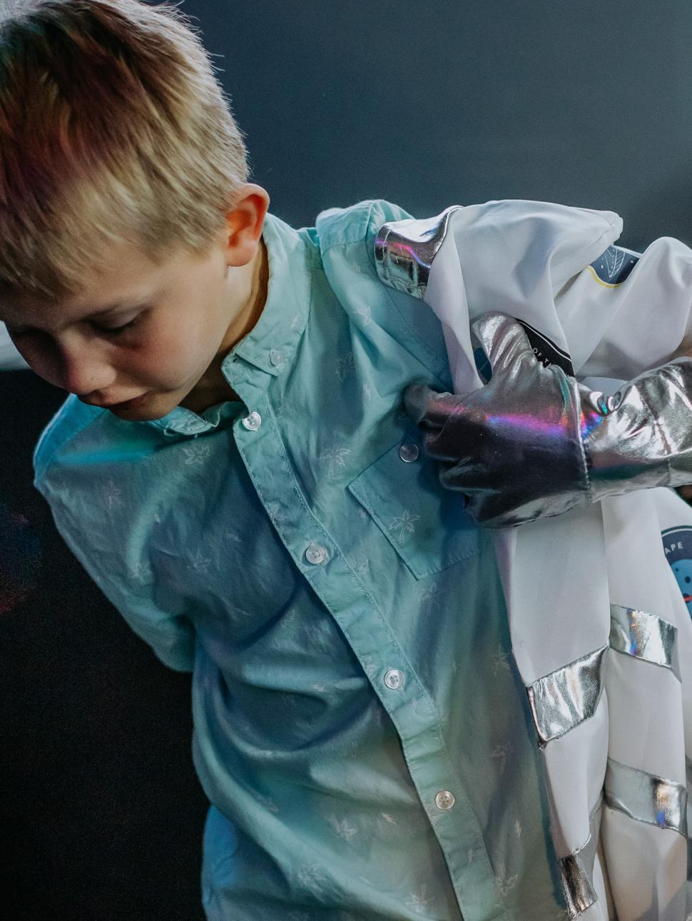 A young child puts on a space suit
