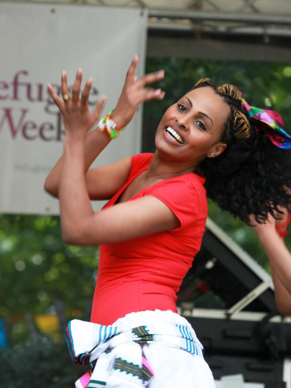 three women in red t-shirts dancing on refugee week stage