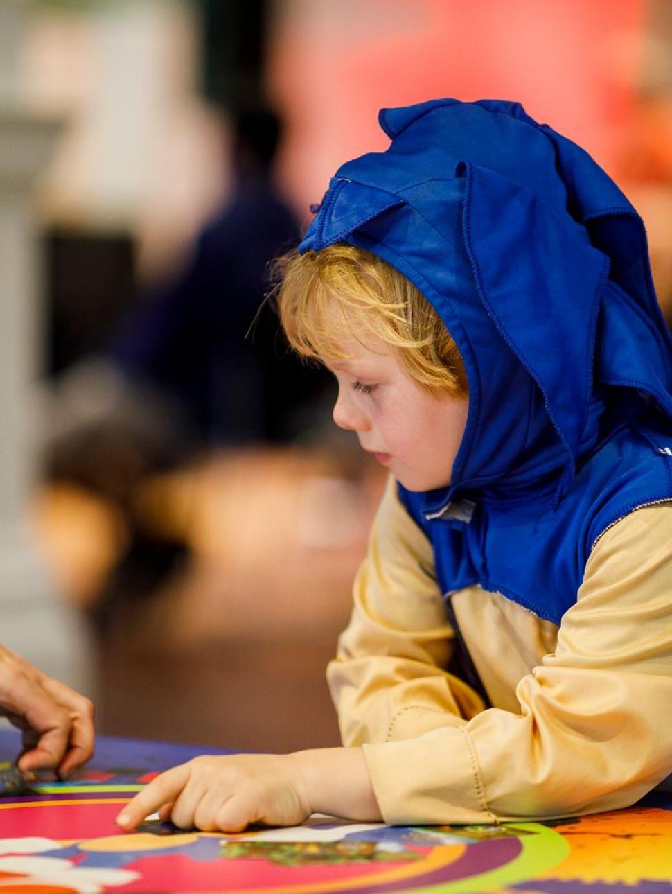 Image of a child in a school holiday workshop wearing a dinosaur 