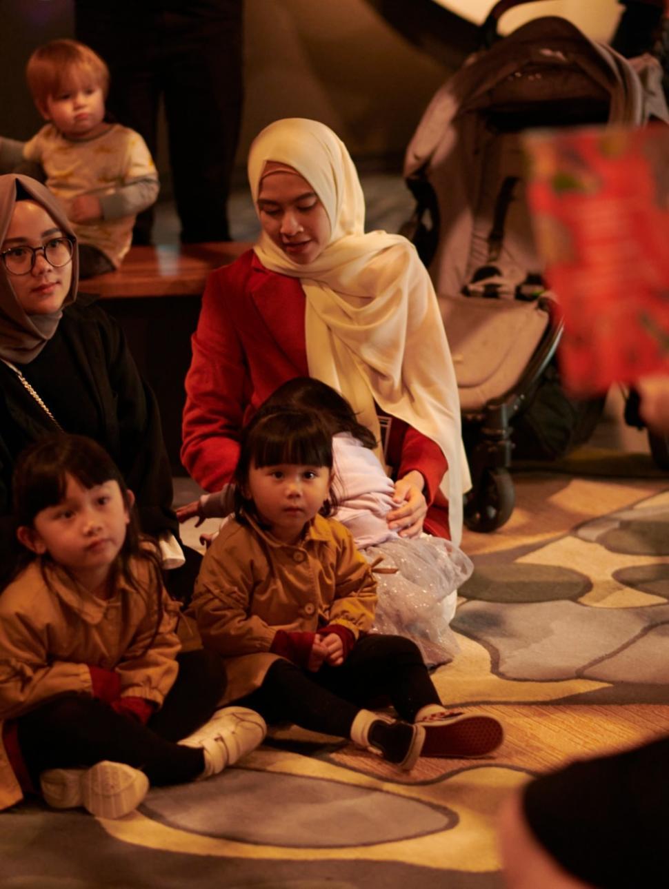 An image of children and adults sitting on the floor listening to story time.