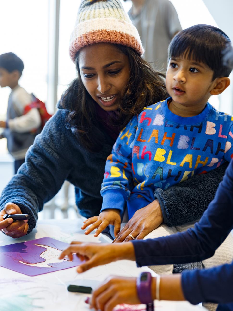 Image of a child in a school holiday drawing dinosaurs with their parent