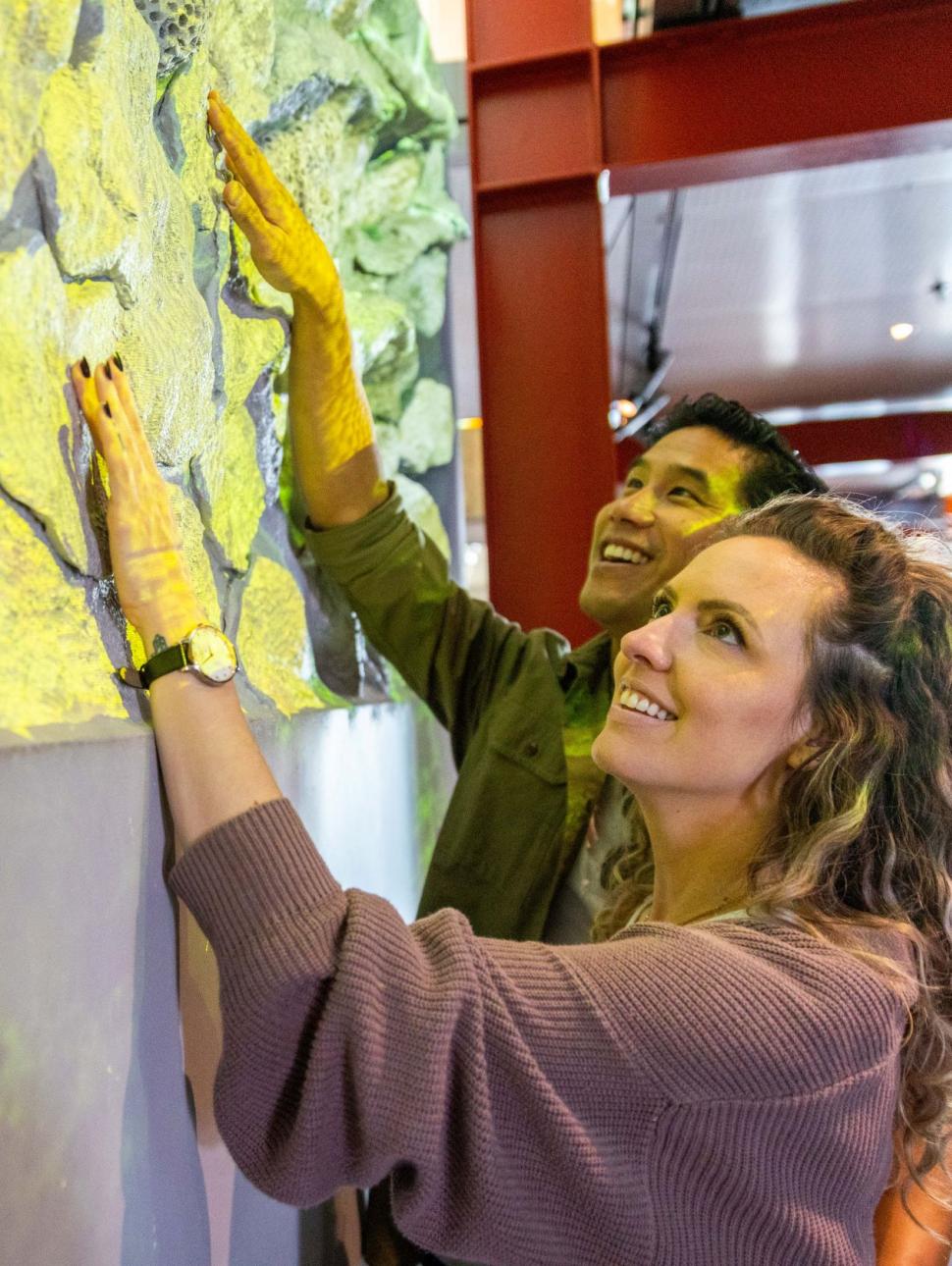 Two people smile while touching tactile wall