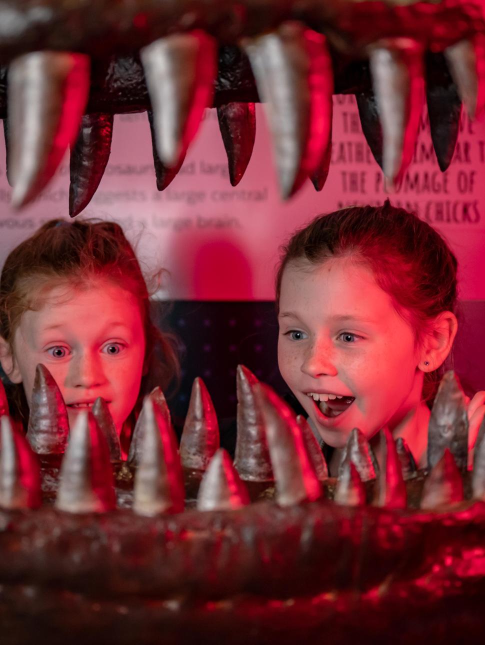 Image of two children posing in the head of a dinosaur skull 