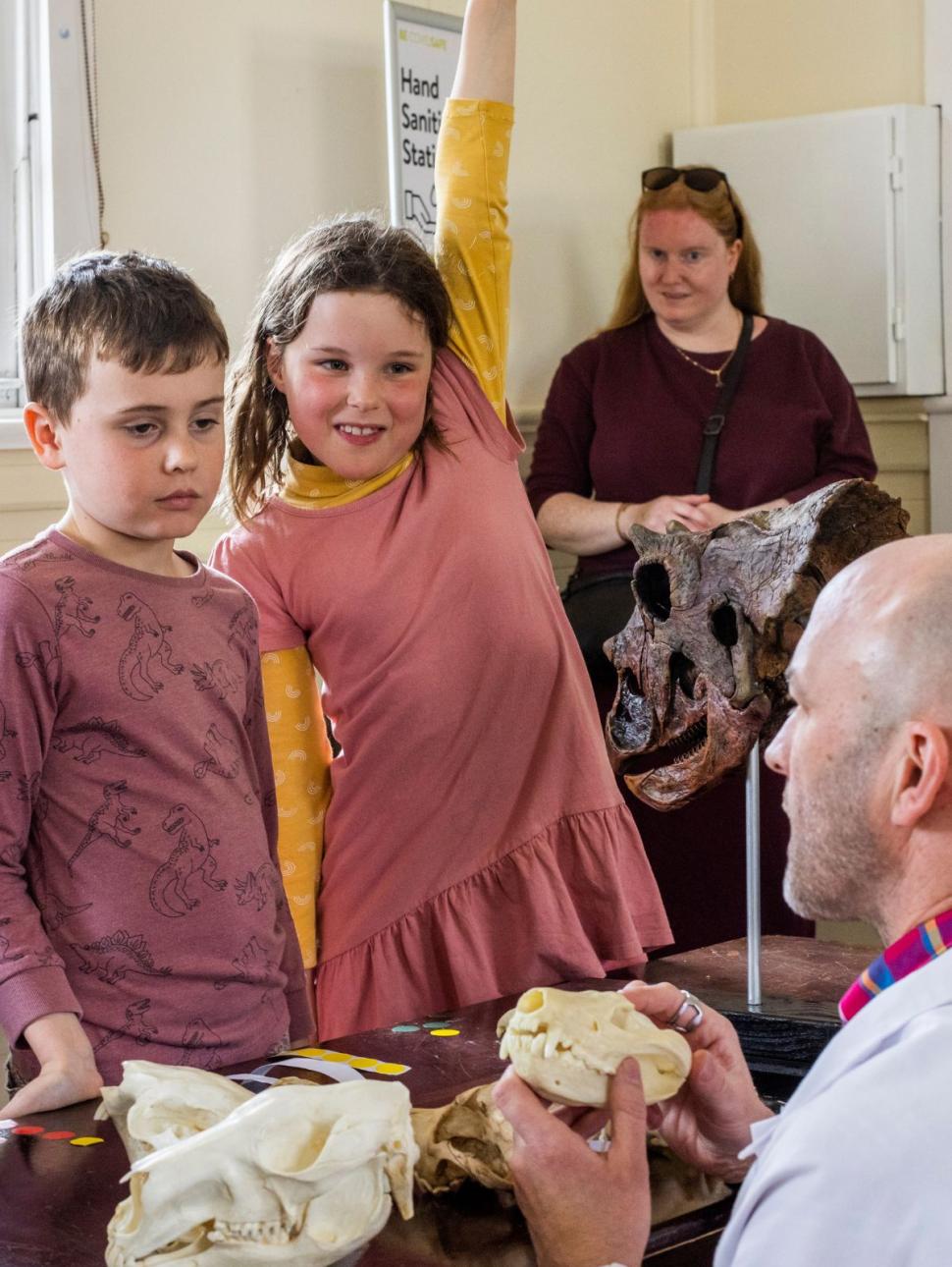 Image of kids in a classroom setting, looking at a skeleton skull being held by a teacher.