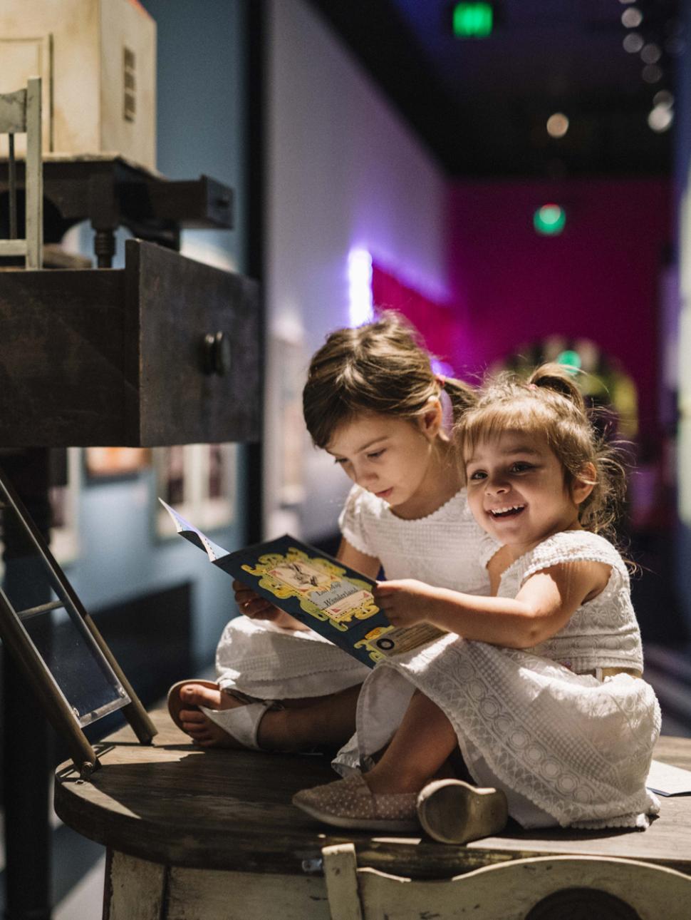 Two small children interact with a book in the Wonderland exhibition.