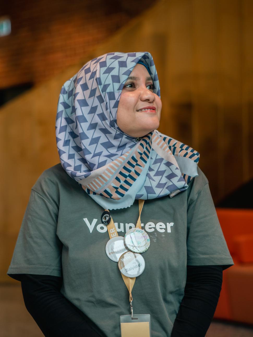 Volunteer Saiyidati looks to the right in a grey shirt, smiling