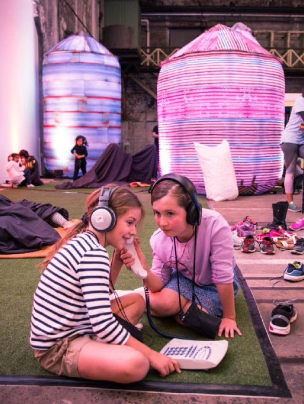 Two kids playing on the floor together with headphones on