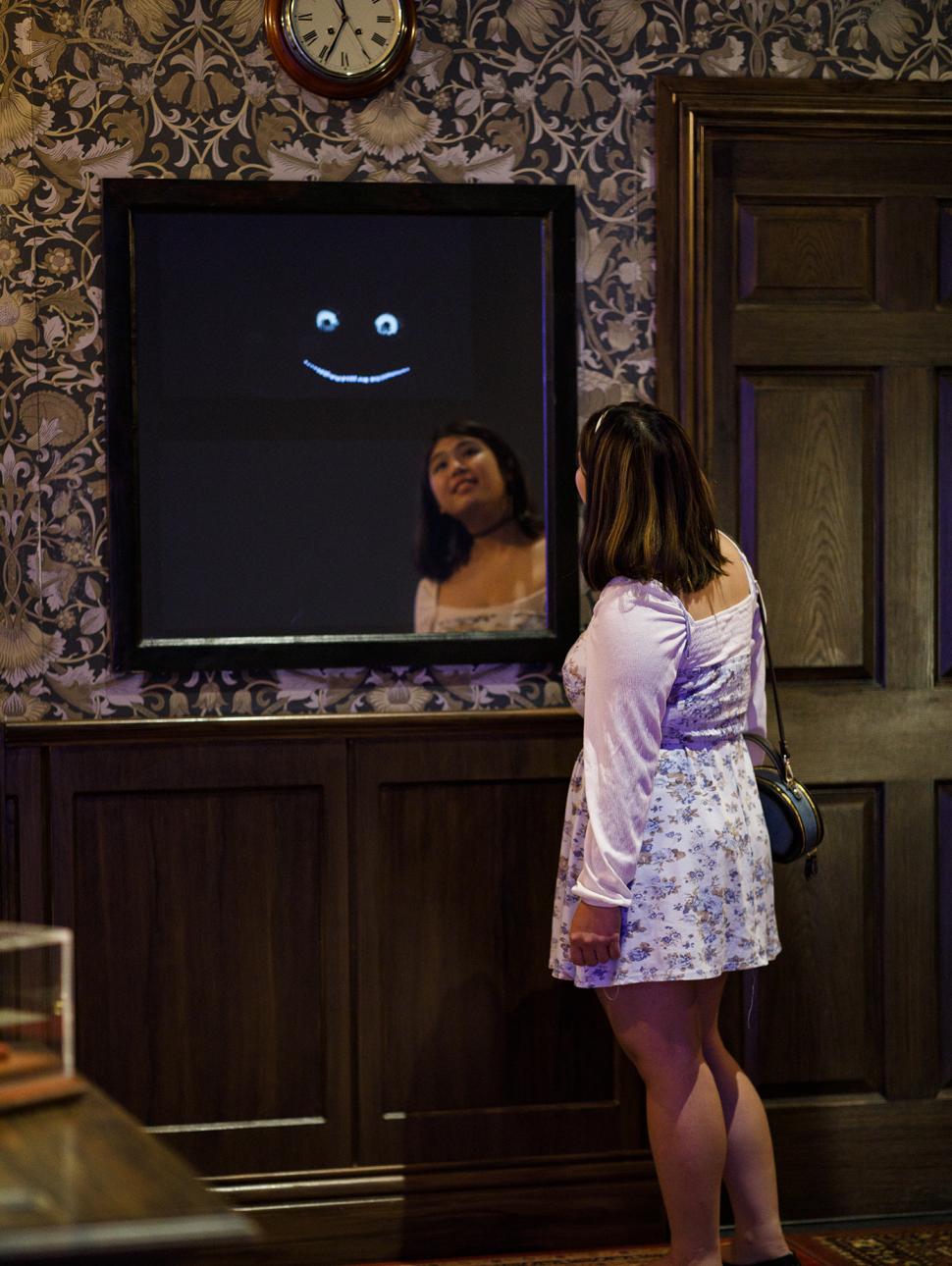 Person in front of a mirror looking into the mirror with a right reflection of eyes and large smiling mouth