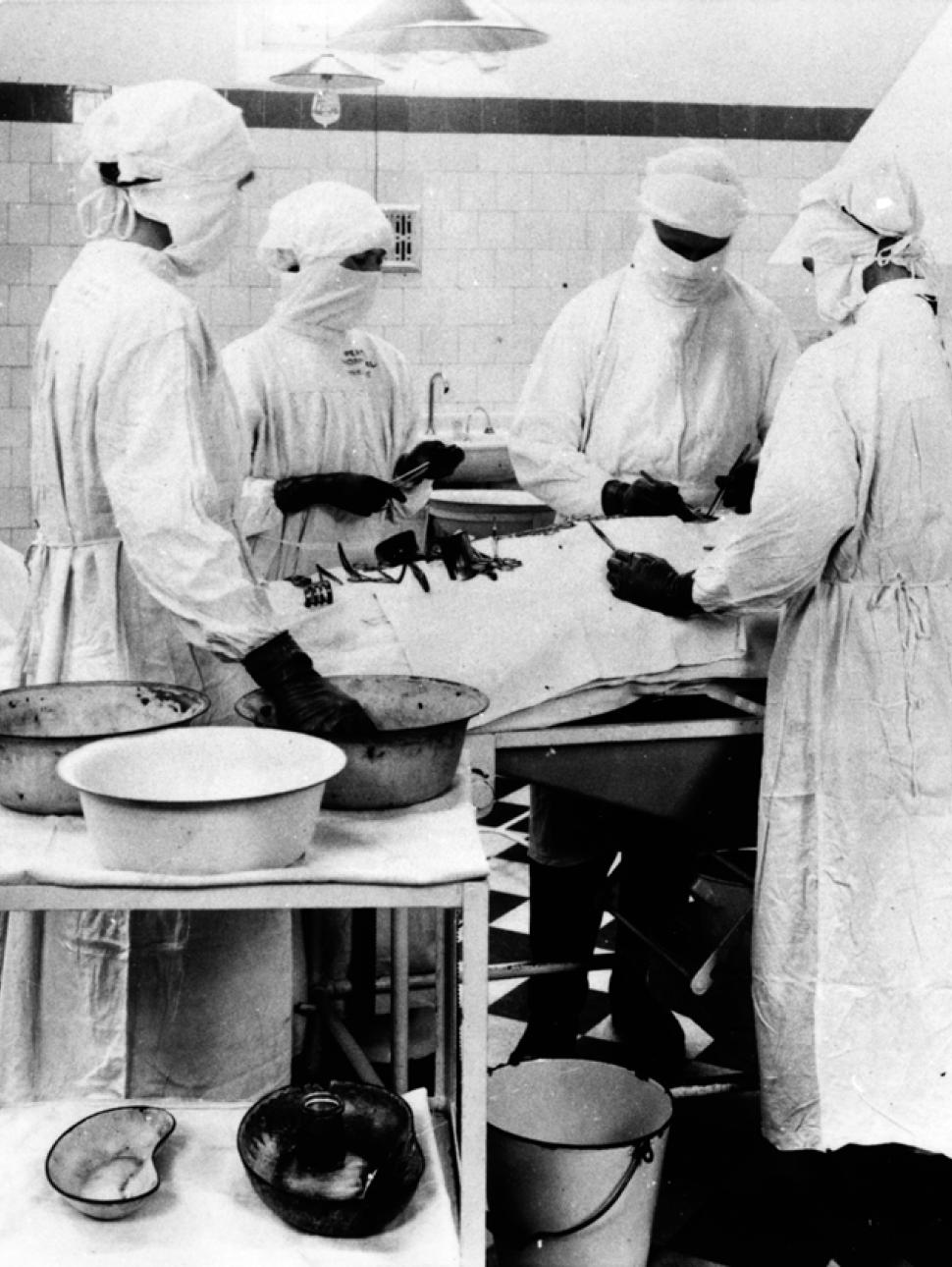 This is an old black and white photograph showing surgical staff in one of the old Perth Hospital's operating theatres 