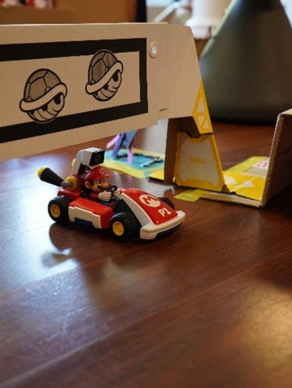 This ismage shows a close up of a Mario Kart car on a race track made by children from recycled materials