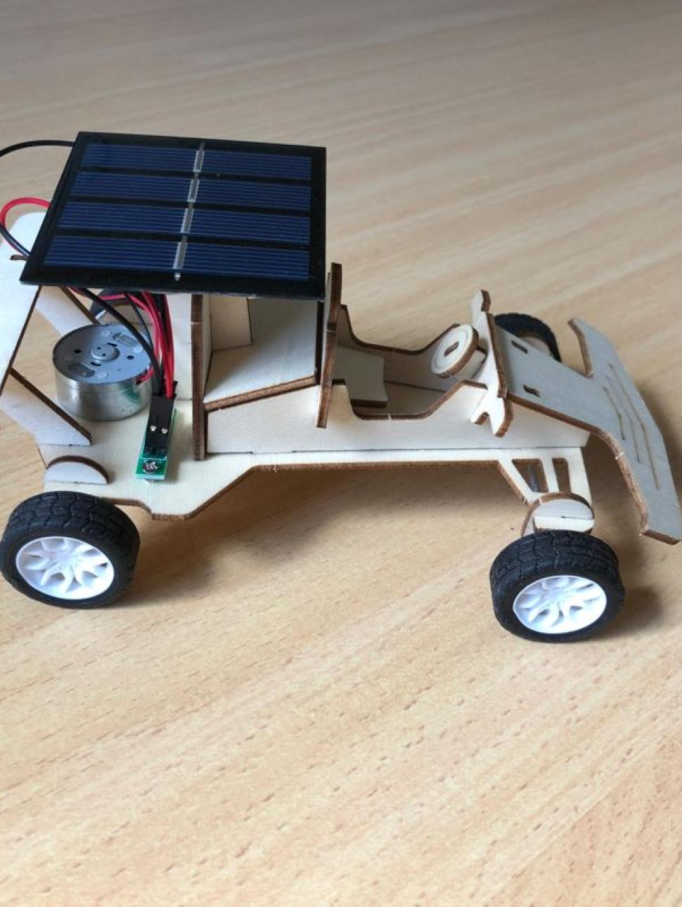 Mini wooden cut out solar car photographed on a wooden table 