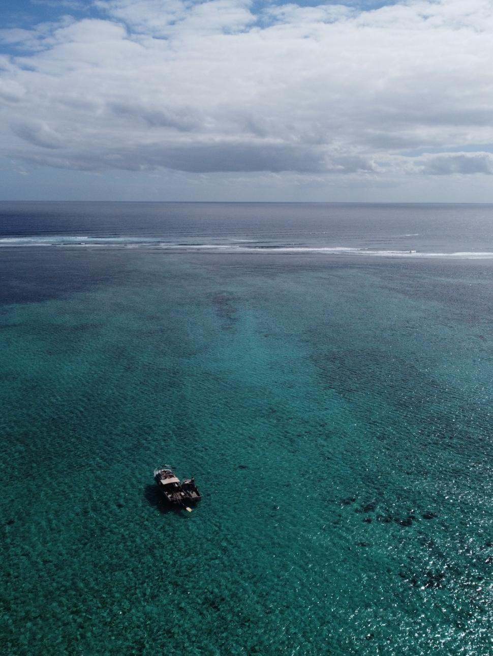 Sweeping aerial view of the ocean with a diving boat in the foreground 