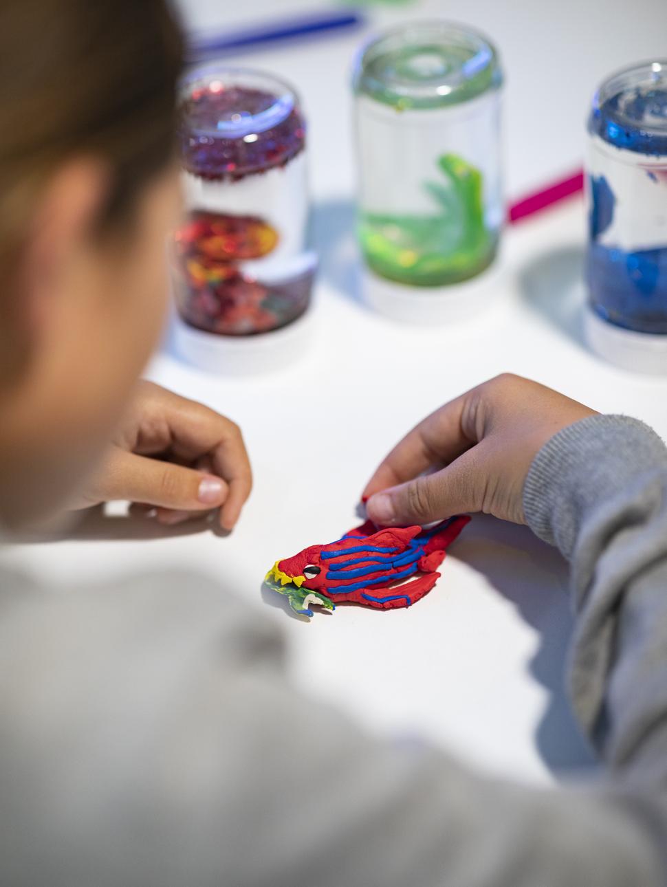 Hands assemble intricate piece of modelling with slow globe jars in the e background