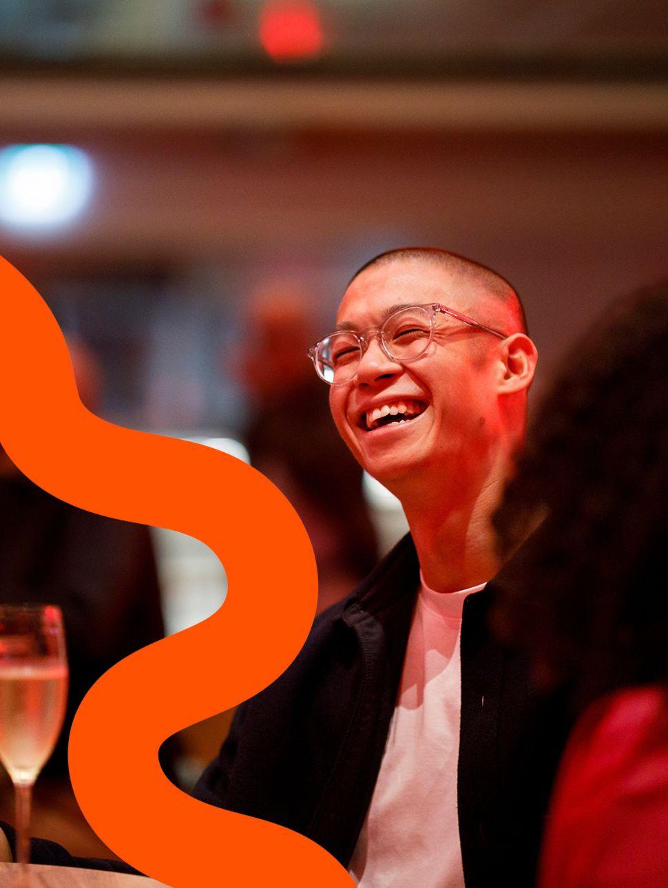 A person laughing away from camera with red lighting around them holding a drink