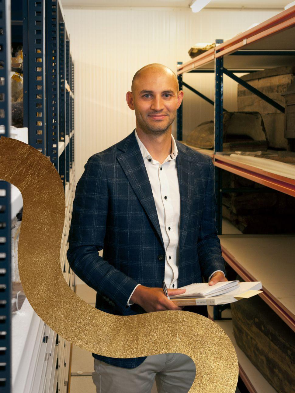 Image of curator standing face on to camerea with paper in his hand