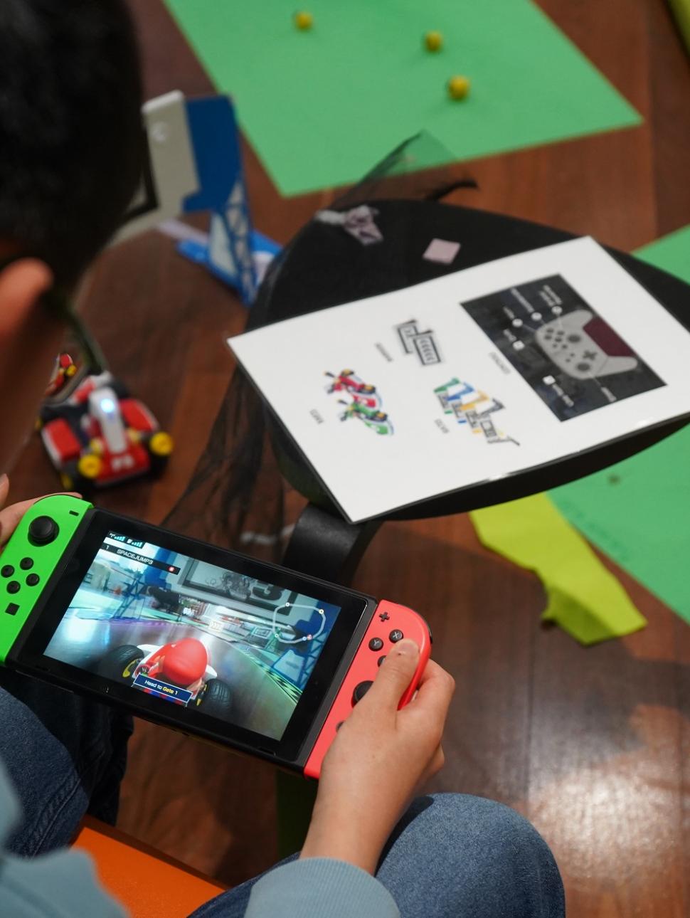 Image shows a boy using a Nintendo Switch to play the game of Mario Kart