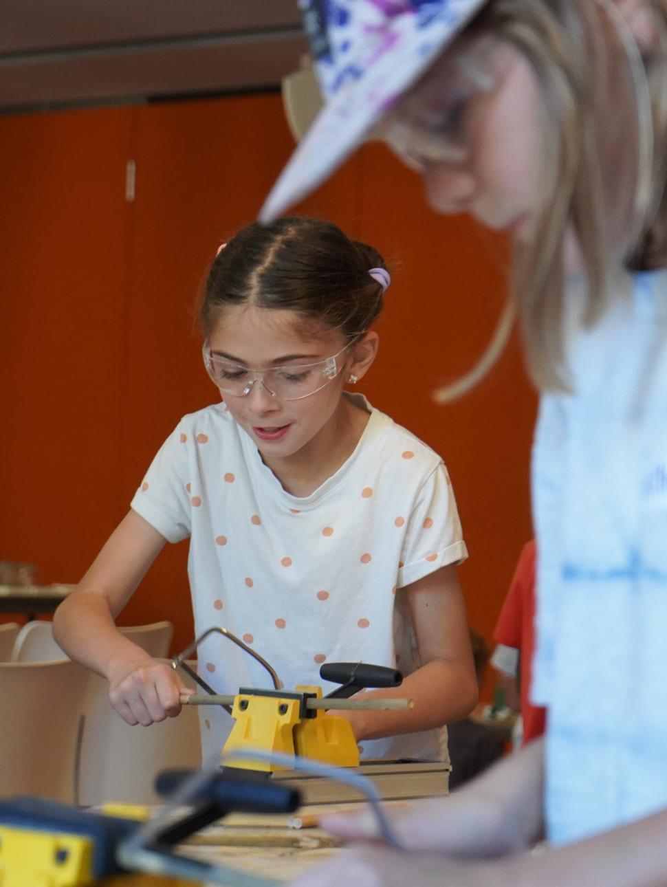 Image shows two children using hand tools to cur bamboo for a bee hotell