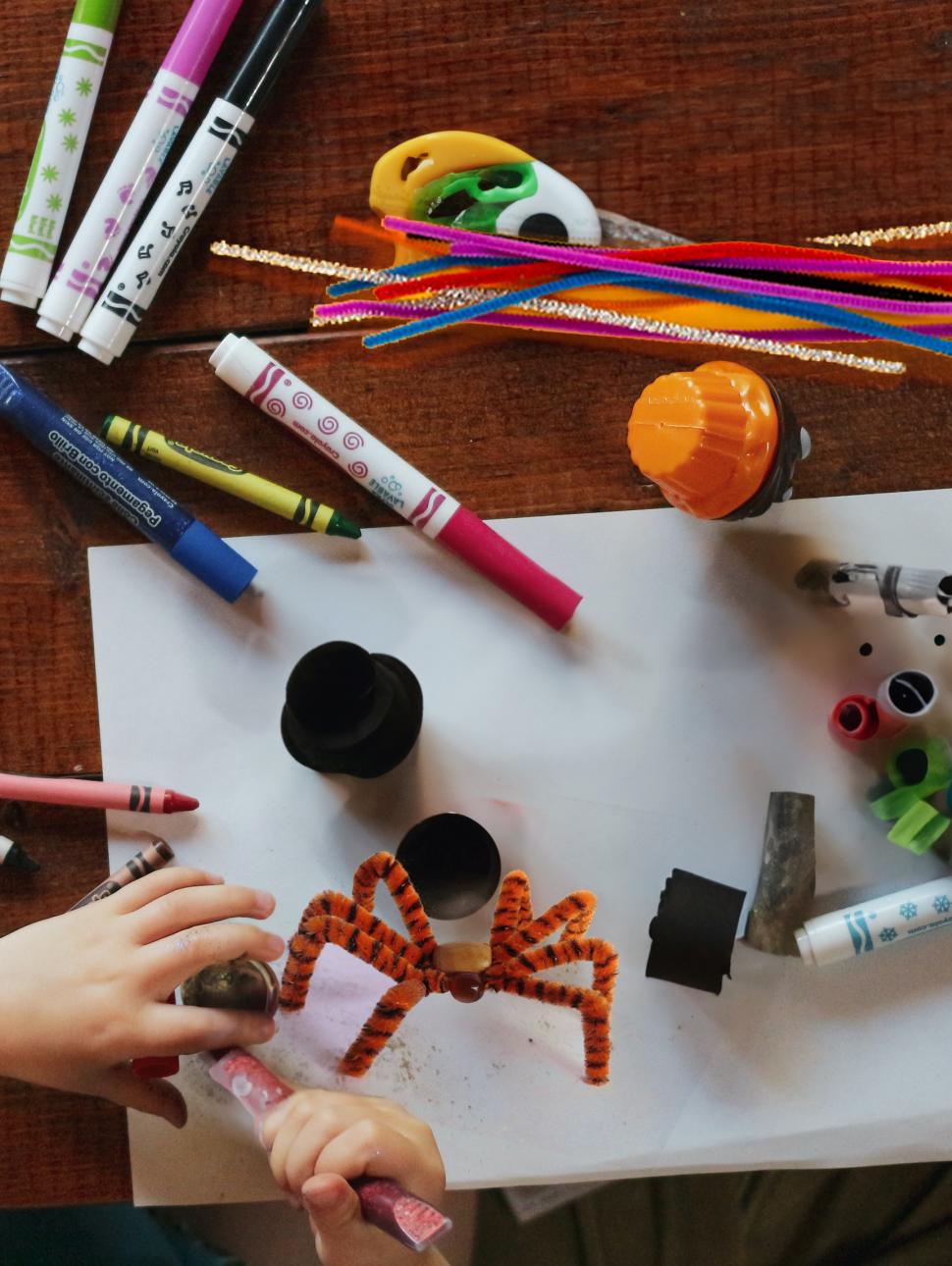 an overhead shot of a desk with crafts and a pipecleaner spider