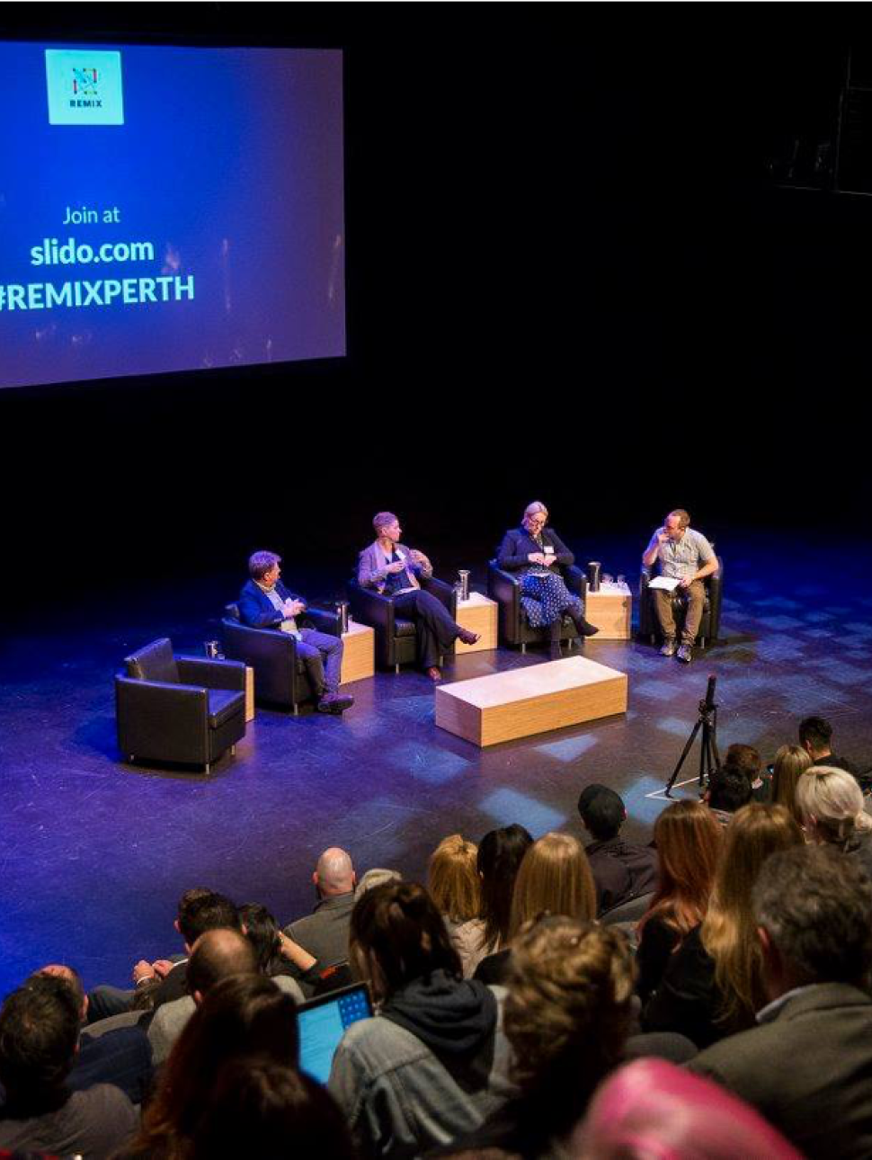 image of speakers on a stage and audience 