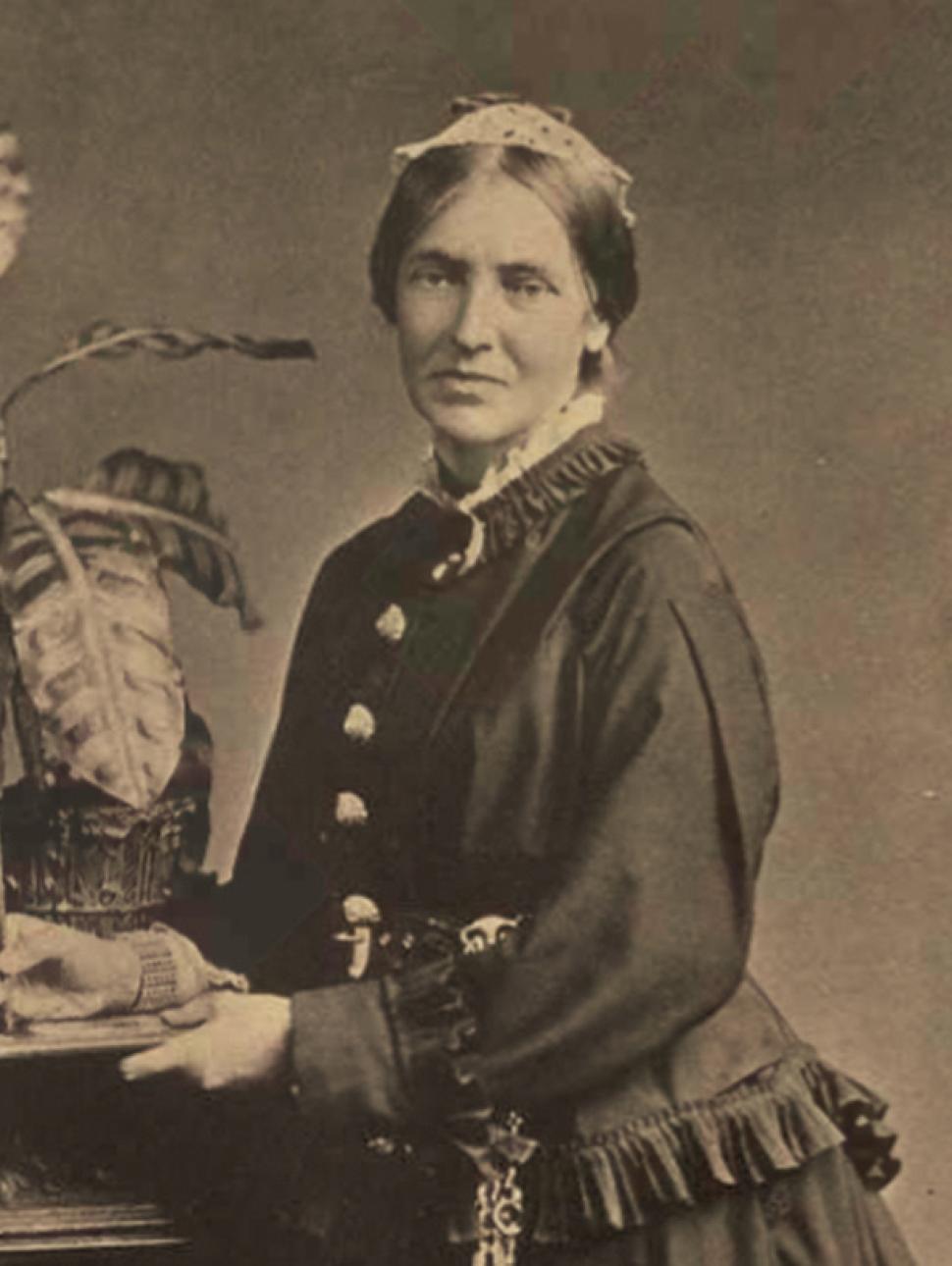 Black and white photo of a women dressed in a layered black dress and white headband.