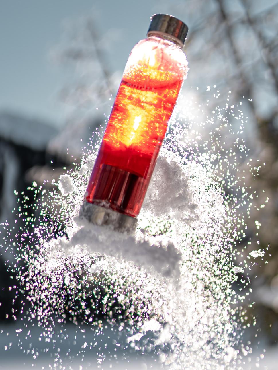 a clear bottle rocket is launching from the ground with a splash from below