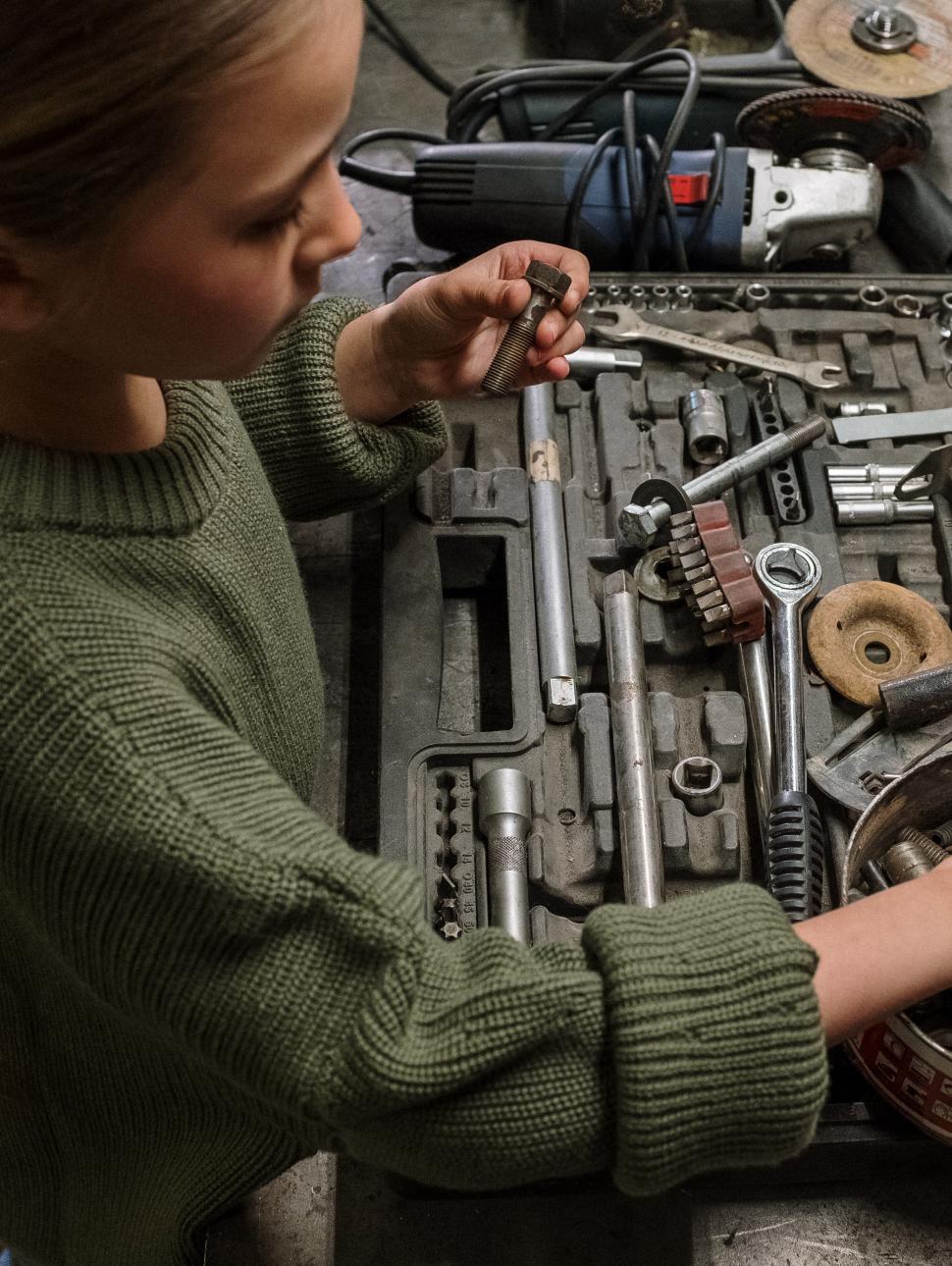 a young girl looks at various mechanics tools