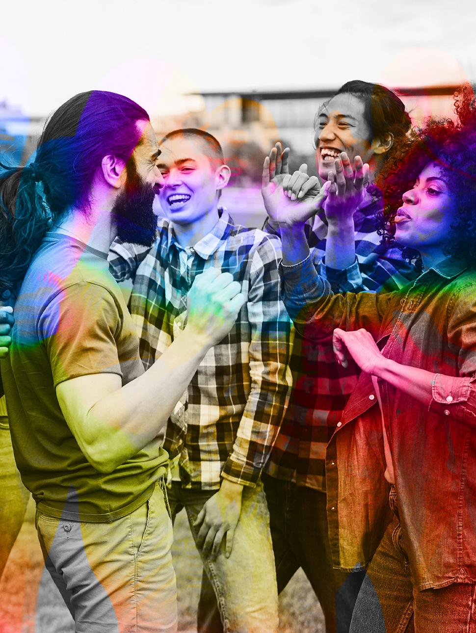 A diverse group of young people having fun dancing outdoors, with a focus on the bearded man's face. The image is black and white but has colourful accents