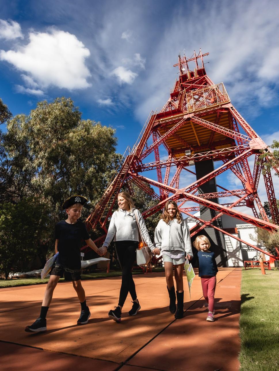 a family of four walks hand in hand smiling outside the Museum