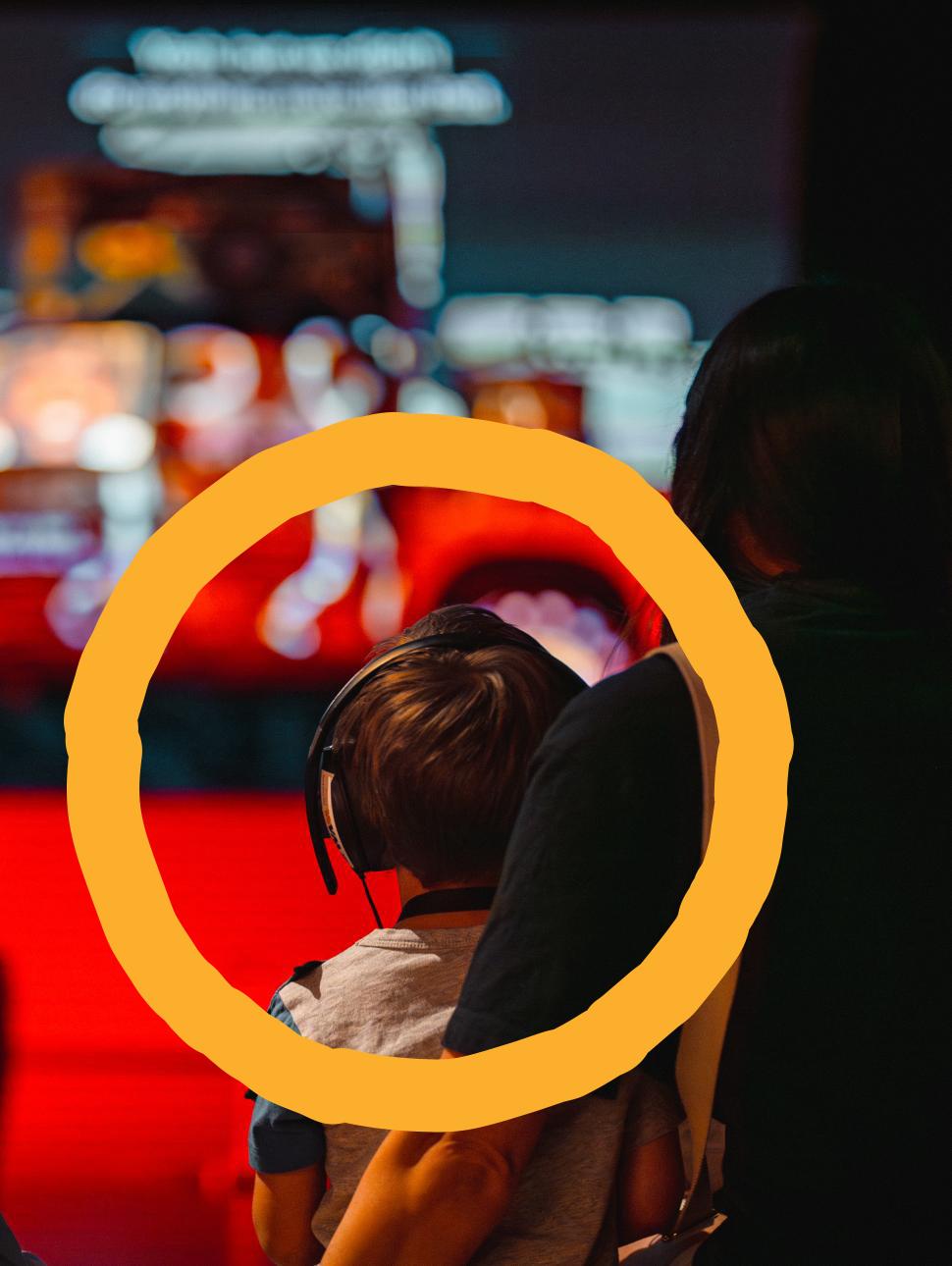 A child looks at the sonic car sculpture in front of them, wearing headphones
