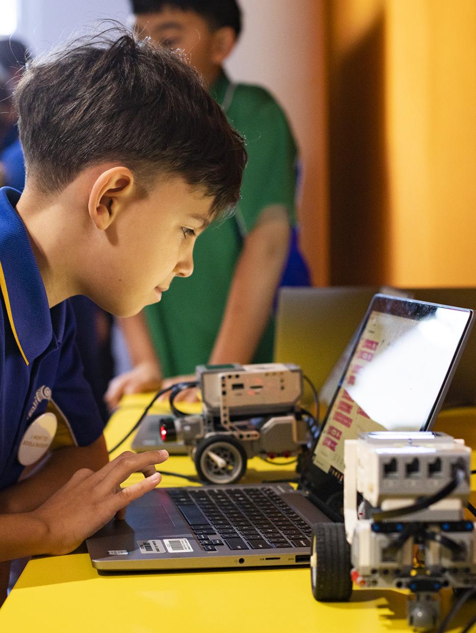child looking into a laptop with a robot connected to the laptop 
