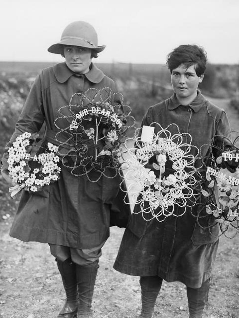 a black and white image of two women holding memorial flower wreath arrangements for