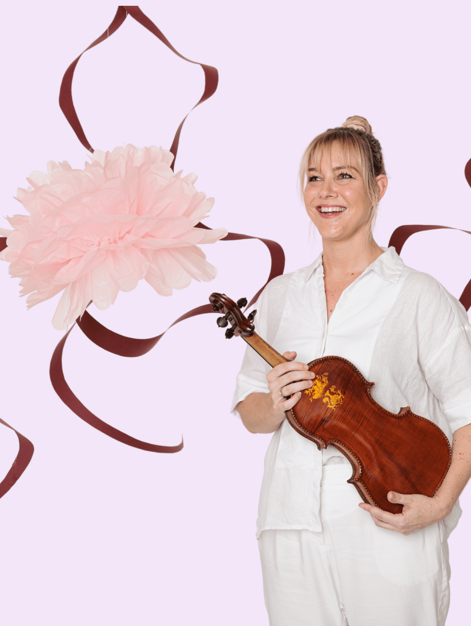 A musician wearing a white pant and shirt set is standing to the right of the frame holding a violin. She is smiling and looking into the distance. The background is light pink and has a pink flower and red ribbon illustration across the back