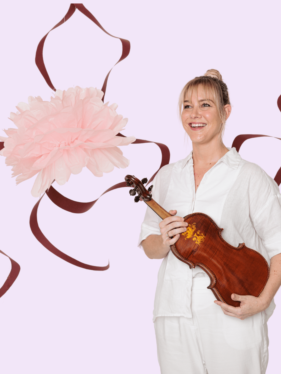 A musician wearing a white pant and shirt set is standing to the right of the frame holding a violin. She is smiling and looking into the distance. The background is light pink and  has a pink flower and red ribbon illustration across the back