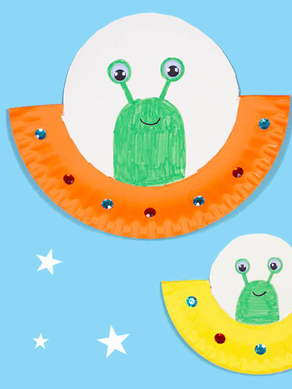 Three paper and drawn green aliens are in different coloured round spaceships in a blue and starry background