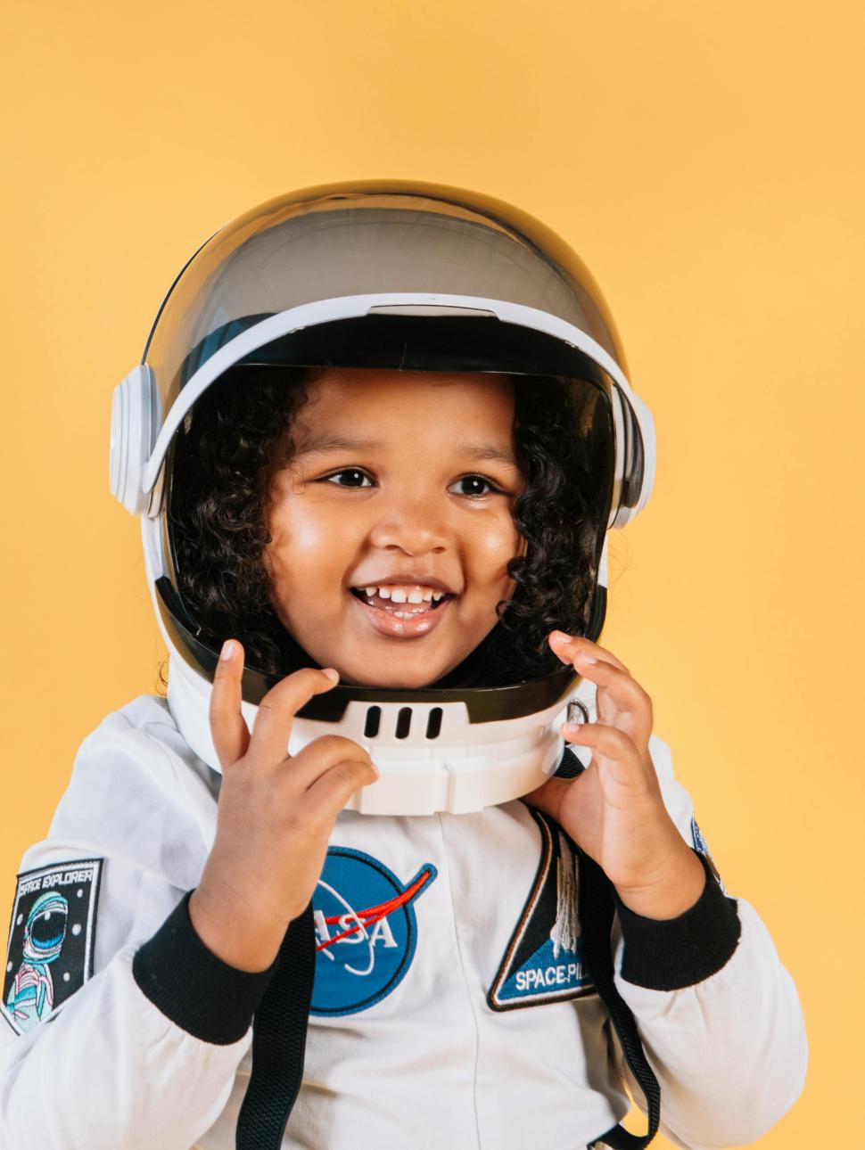 a young child smiles and has a space suit and helmet on