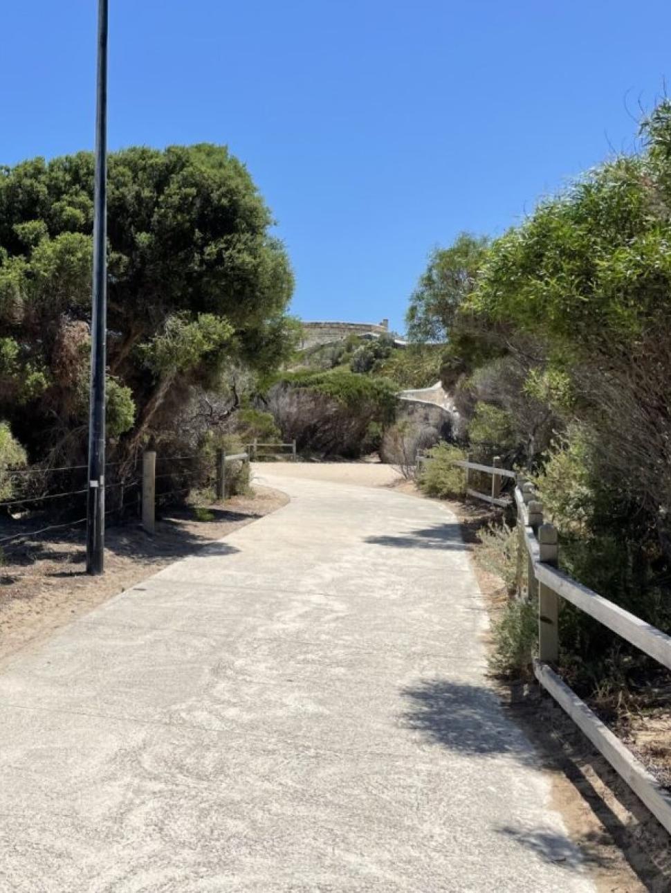 Walyalup walking trail pathway surrounded by trees and shrubs leading to the Maritime Museum pictured in the distance