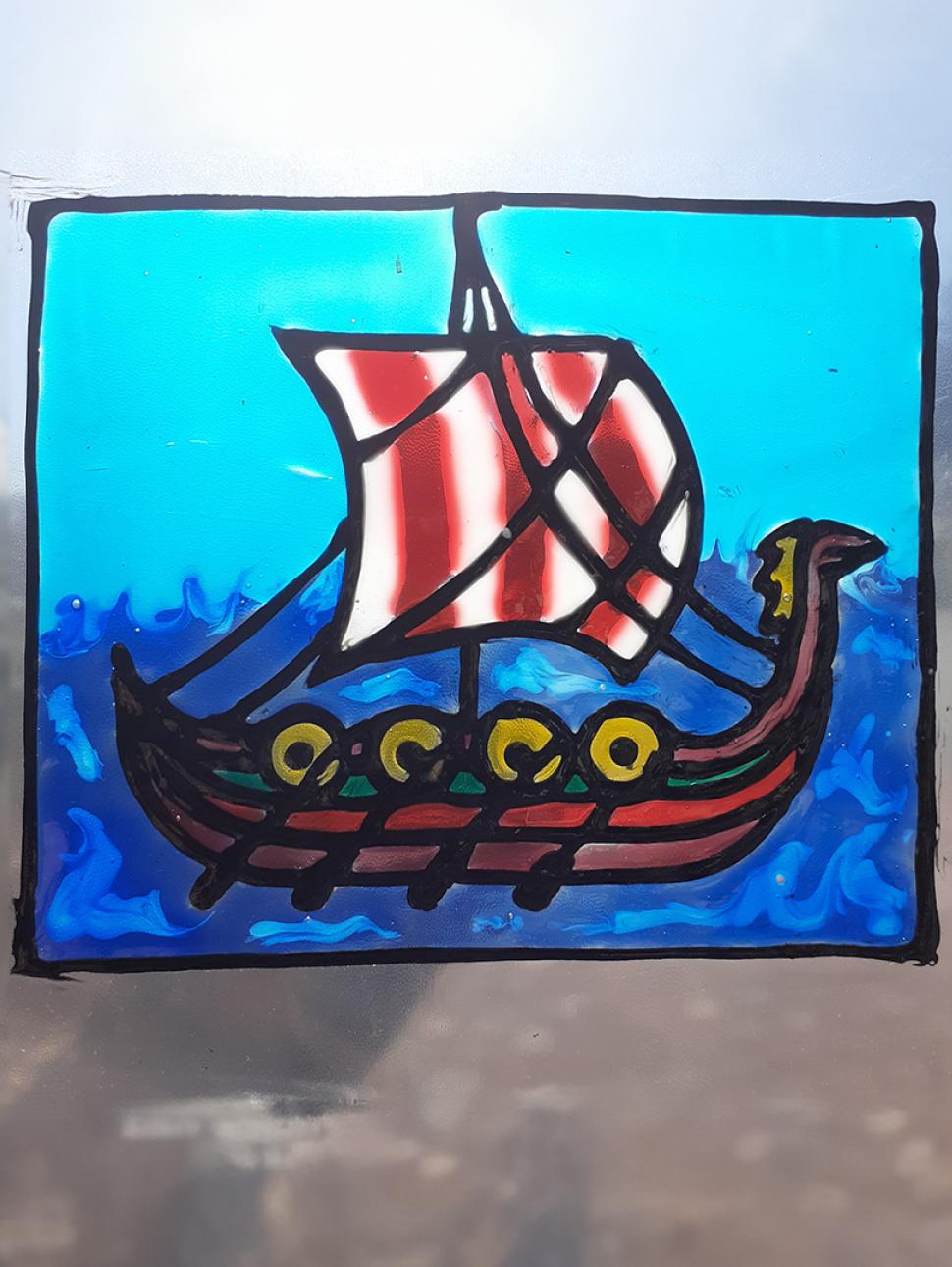 a handmade stained glass window suncatcher design of a viking long boat with colourful sails on the ocean