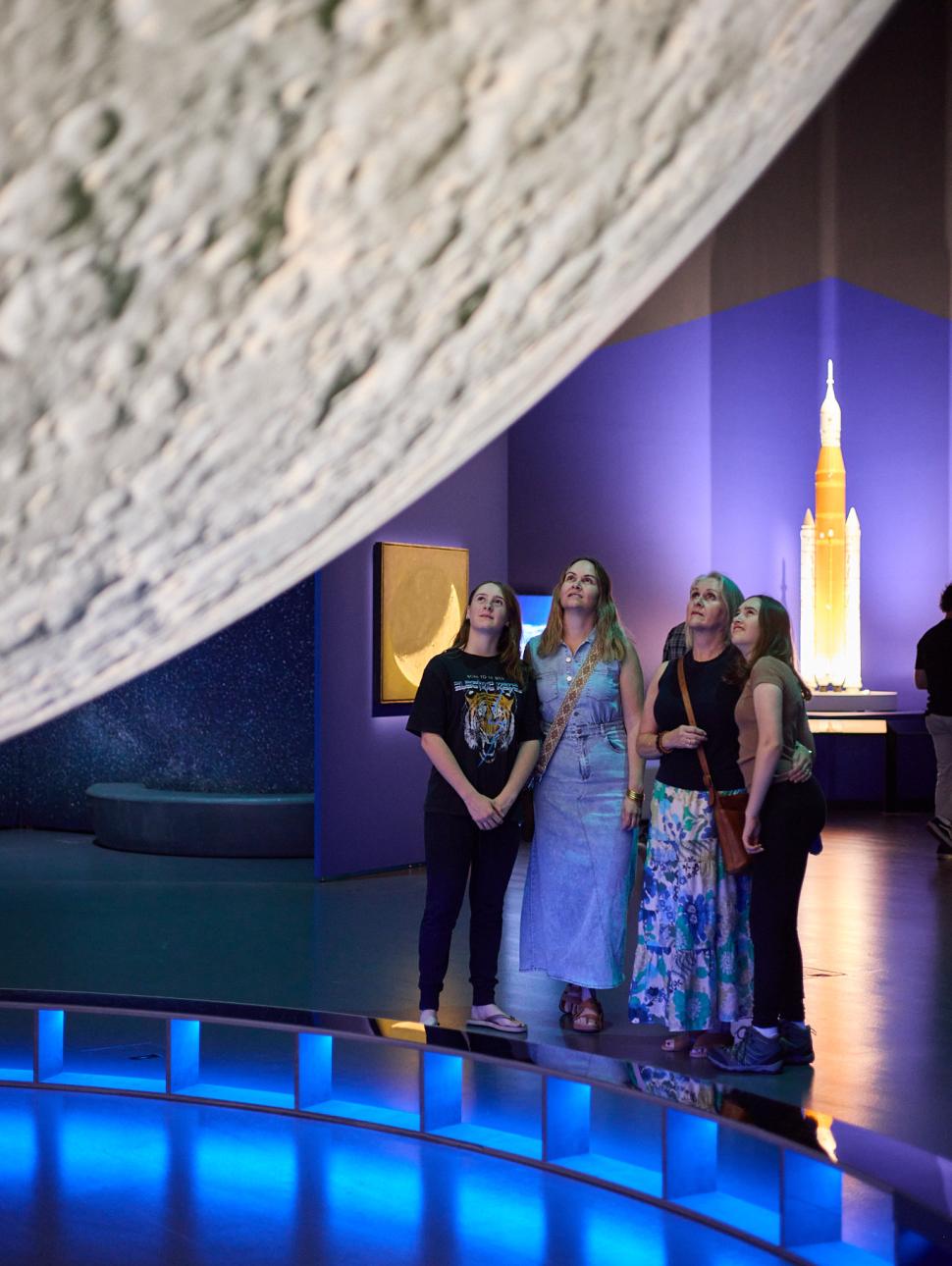 four women looking upward toward the moon