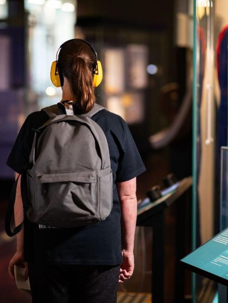 A woman wearing headphones examines a display of artifacts, immersing herself in the rich history they represent.