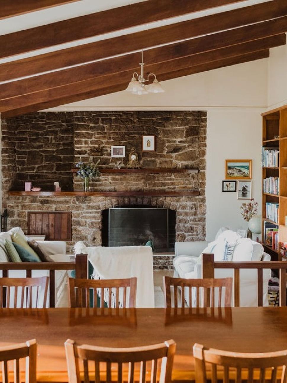 a room in a homestead with dining tables chairs and fireplace