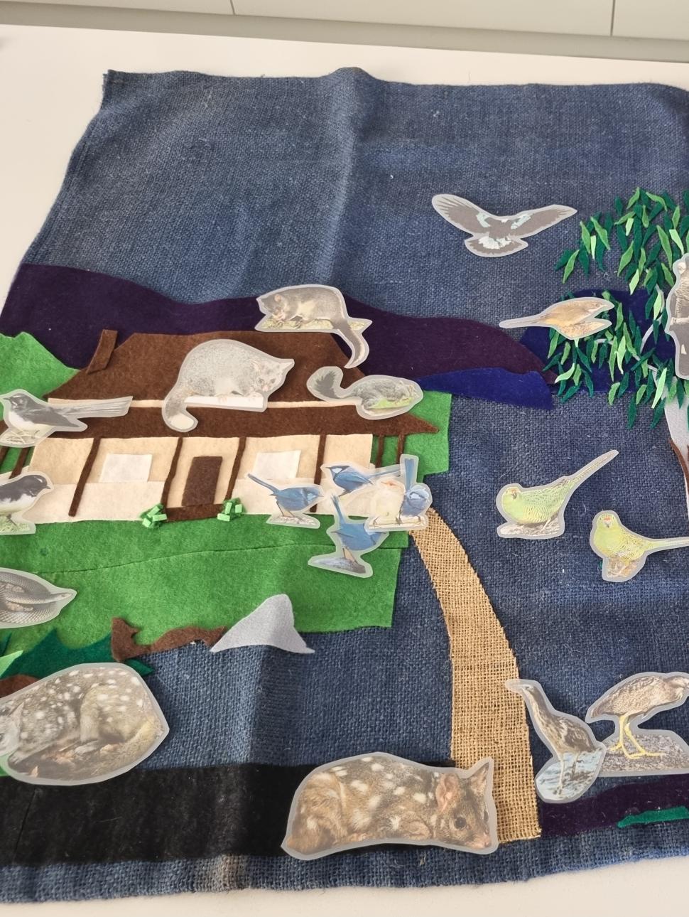 a close up of paper craft native animals on a felt board